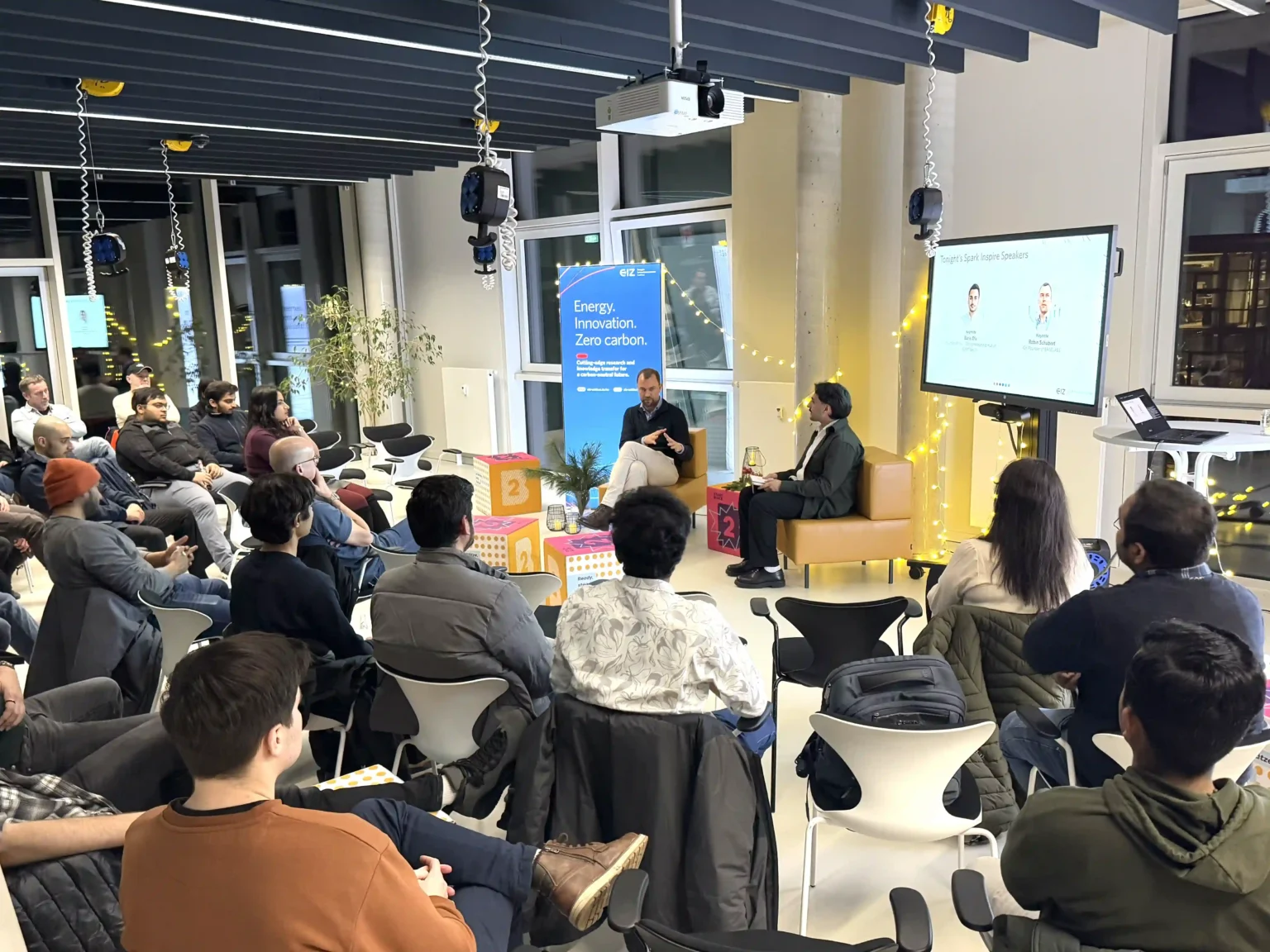 Menschen sitzen im Halbkreis vor einem Panel.